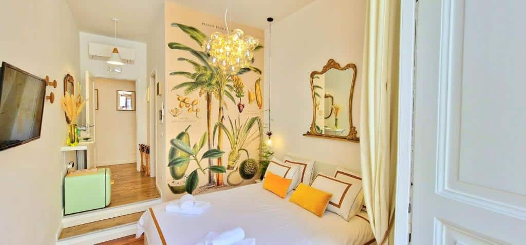 Quarto do Napoli Tree com paredes decoradas com painel floral e espelho dourado, iluminado por lustre, mobília retro e acessórios em tons pastel.