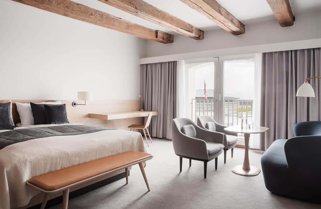 Quarto do Copenhagen Admiral Hotel com cama de casal, poltronas, duas mesas, cadeira e uma chaise longue ao fundo da cama. Tem também uma varanda.