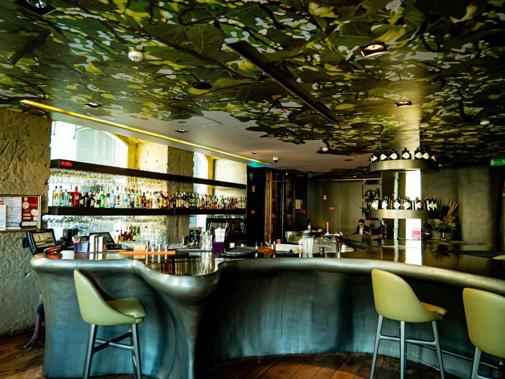 Bar do Figueira by The Beautique Hotels em estilo contemporâneo, em tons de verde musgo, com balcão de formato orgânico e teto pintado com flores.