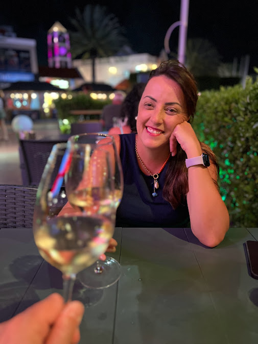 Mulher a sorrir num restaurante à noite, com um copo de vinho branco, em Aruba