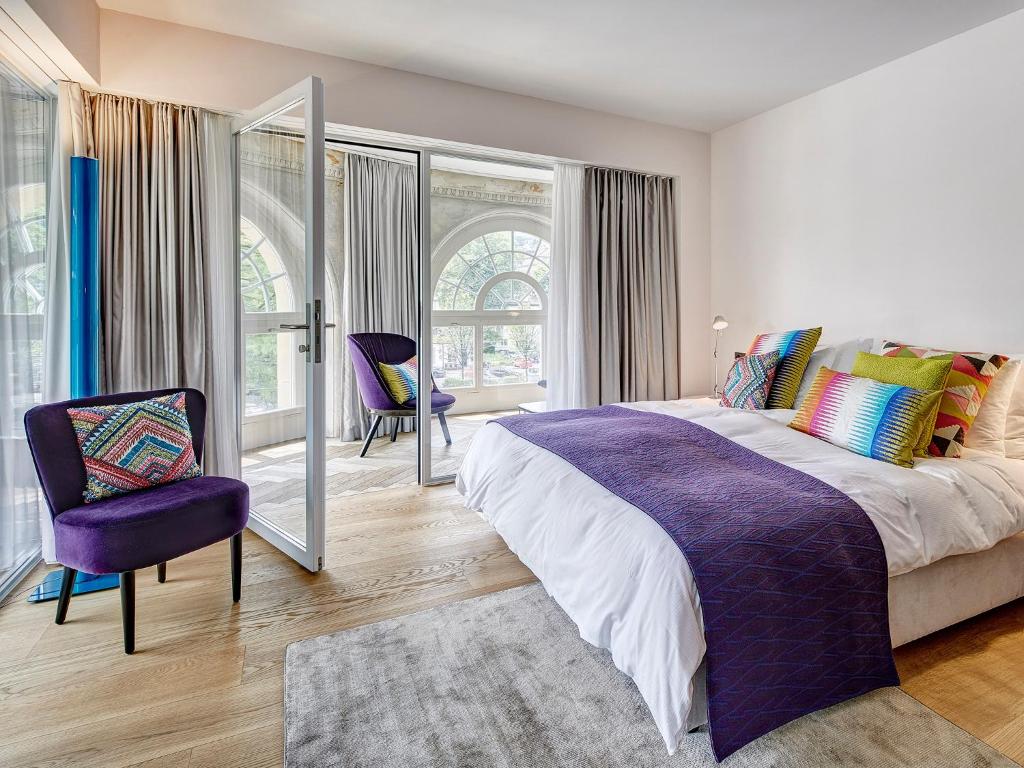 Quarto do Hotel Anker Luzern, em Lucerna, com cama de casal e poltrona roxa.