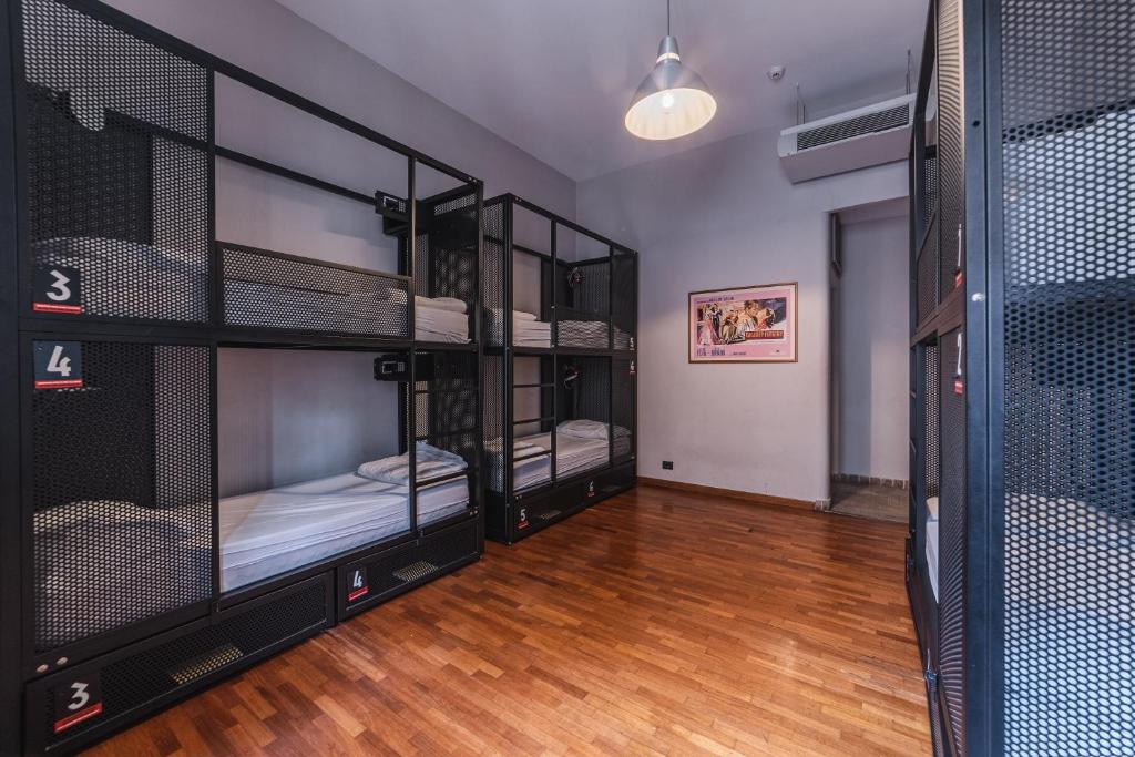 quarto do YellowSquare Rome, uma das opções de onde ficar em Roma, com chão que imita madeira, beliches com armários trancados e estrutura em ferro, com decoração moderna