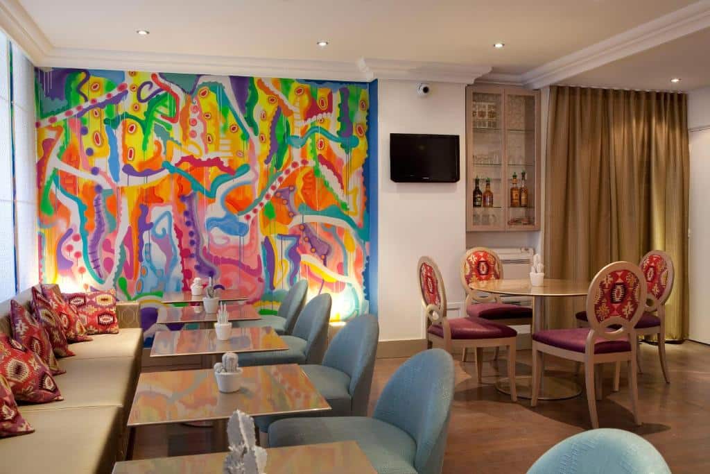 Mesas para refeições no Hôtel Mayet, com uma obra de arte na parede ao fundo