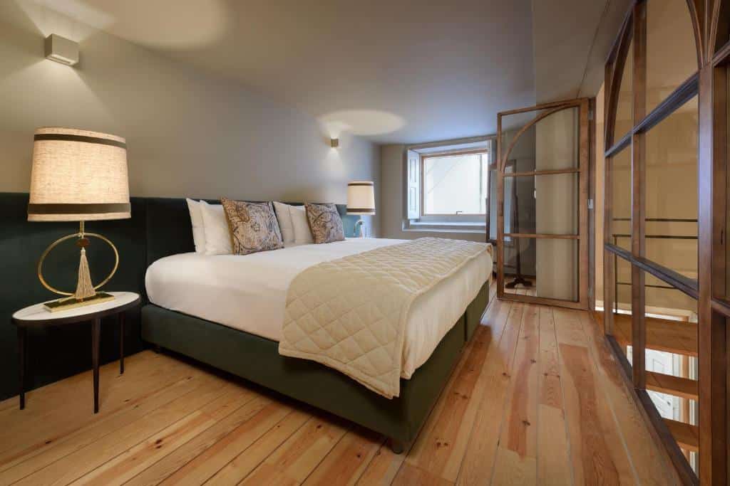 Quarto do Condes de Azevedo Palace Apartments, com cama de casal à esquerda e uma cómoda com candeeiro.