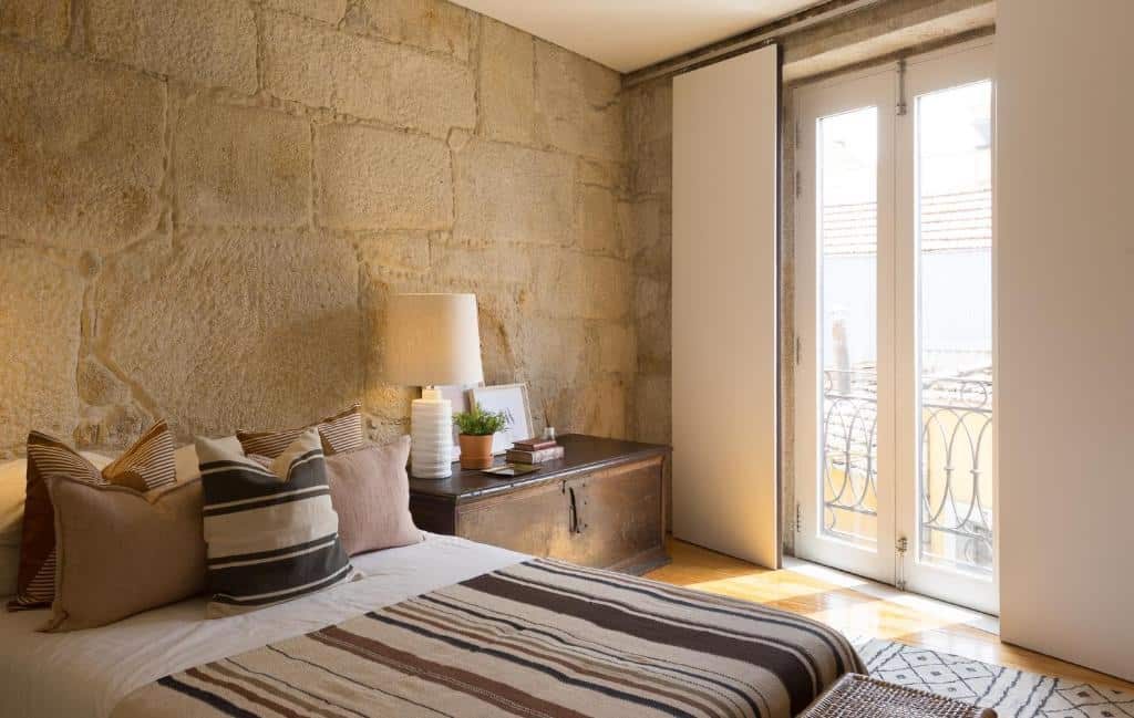 Quarto da Casa Castanha, com cama de casal à esquerda e uma cómoda de madeira à direita com candeeiro.