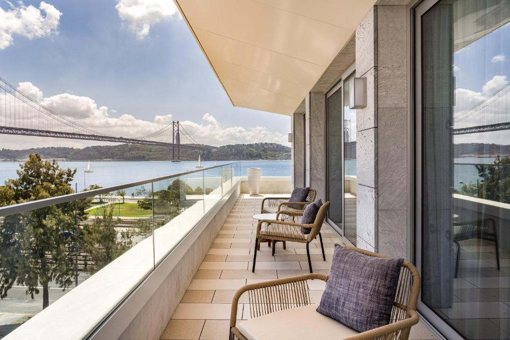 Varanda dos quartos do Hyatt Regency Lisbon com cadeiras e almofadas e vista para o rio Tejo