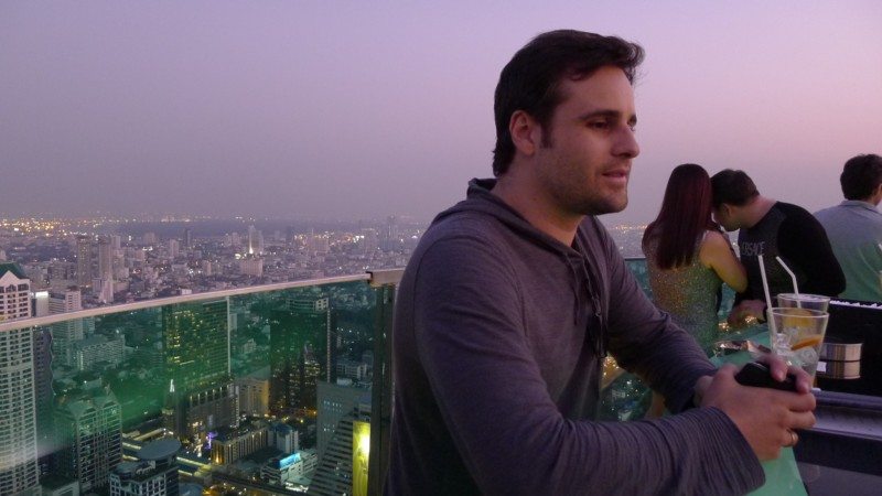 Vista de uma esplanada no topo de um arranha-céus sobre a cidade ao anoitecer, no Sky Bar, em Banguecoque.