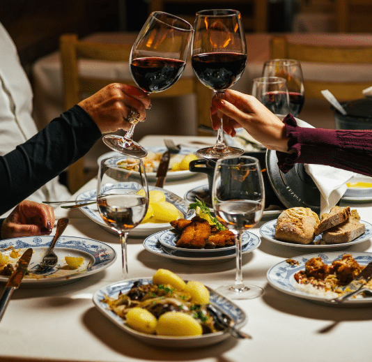 Mesa da Adega São Nicolau com vários pratos e taças de vinho.
