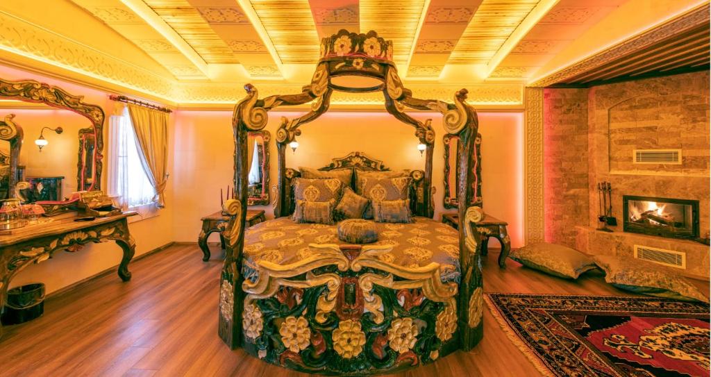 Quarto ornamentado do Kapadokya Hill Hotel & Spa, um dos hotéis da Capadócia, com cama de dossel esculpida, roupa de cama estampada, lareira e iluminação amarela quente.