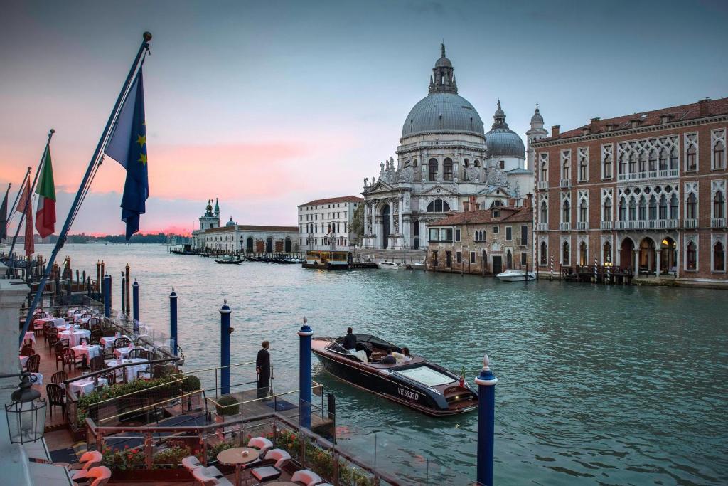 Bela vista da Basílica de Santa Maria della Salute e do Grande Canal em Veneza, Itália, com embarcações típicas ao pôr do sol