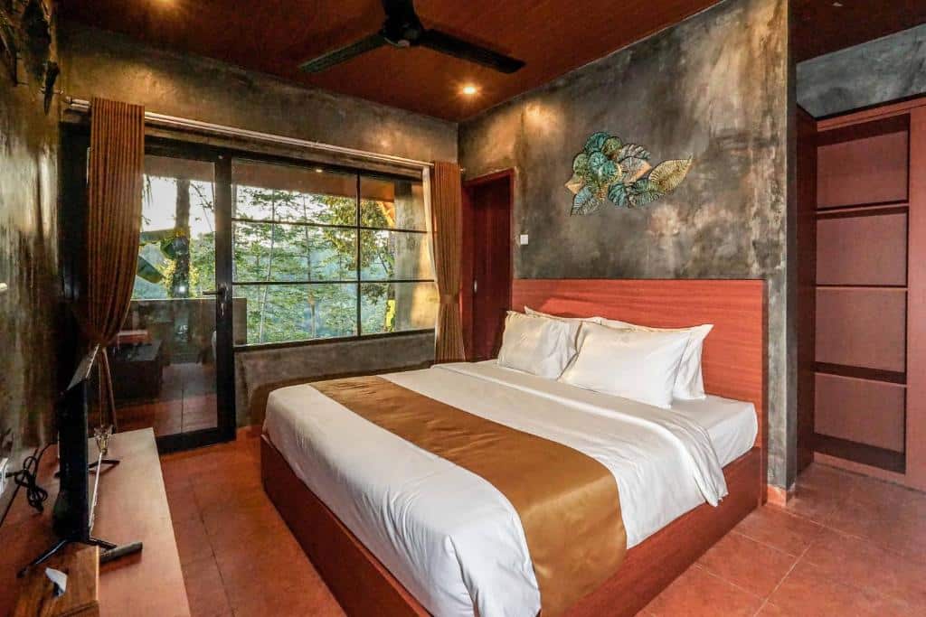 Quarto acolhedor com cama grande, roupa de cama branca e castanha e janela ampla, no Daydream Lodge, em Bali.