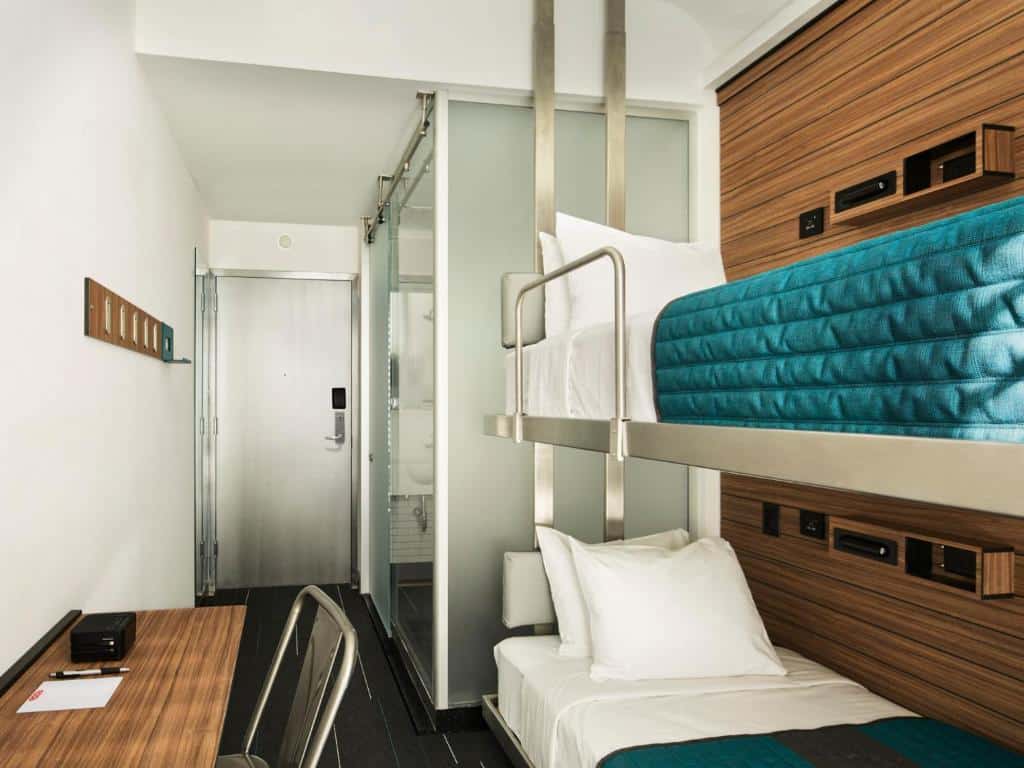 Quarto do Pod Times Square com um beliche de solteiro à direita, uma secretária de trabalho à esquerda e uma casa de banho ao fundo.