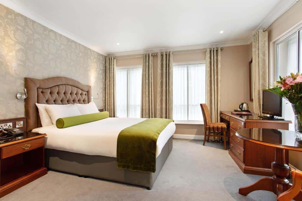 Quarto do Drury Court Hotel com cama king size, decoração em tons neutros e mobiliário de madeira escura.