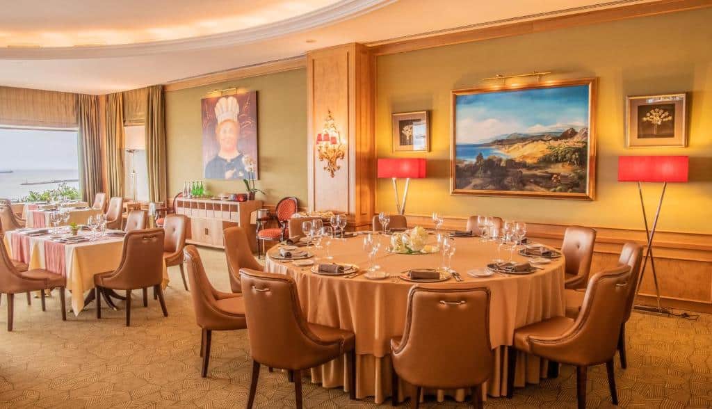 Sala de refeições do Hotel Cascais Miragem Health & Spa, com mesas, cadeiras e obras de arte nas paredes.
