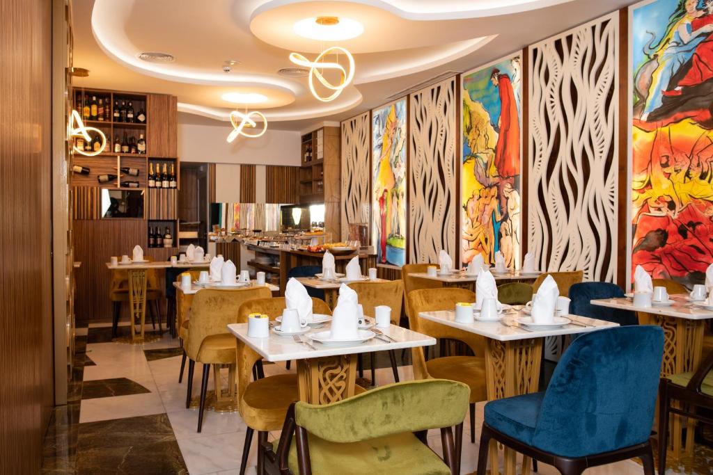 Sala de refeições do Be Poet Baixa Hotel com uma parede decorada com pinturas coloridas, mesas de madeira e cadeiras estofadas em cores variadas.