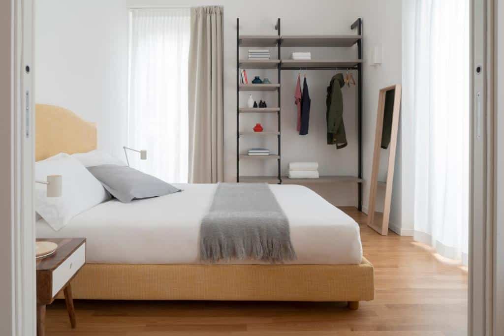 Quarto do Brera Apartments in San Babila com uma cama de casal, uma janela com cortinas, um roupeiro aberto, chão em imitação de madeira e um espelho de corpo inteiro