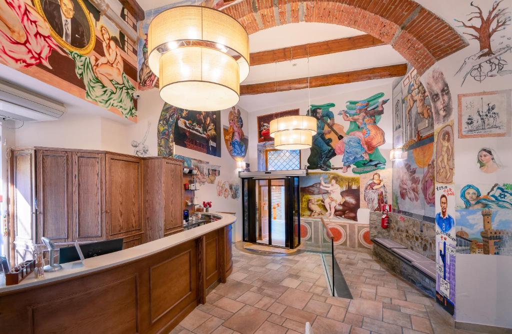 Receção do Hostel Archi Rossi, com pinturas coloridas na parede, balcão de madeira e dois candeeiros redondos suspensos no teto