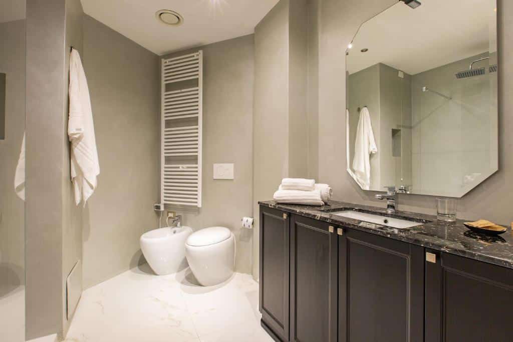 Casa de banho do Missori Suites com uma cabine de duche, um bidé e uma sanita, um móvel de madeira preta com o lavatório, um espelho amplo e toalhas brancas