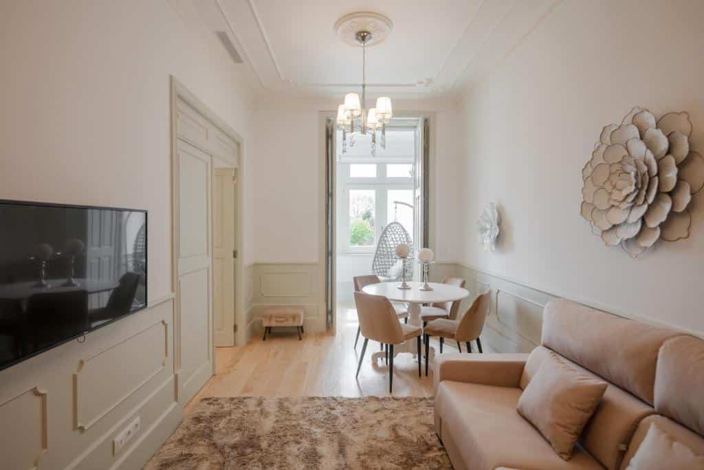 Sala do Porto Deluxe Apartments, com sofá à direita, uma TV em frente e, ao fundo, uma mesa redonda com cadeiras.