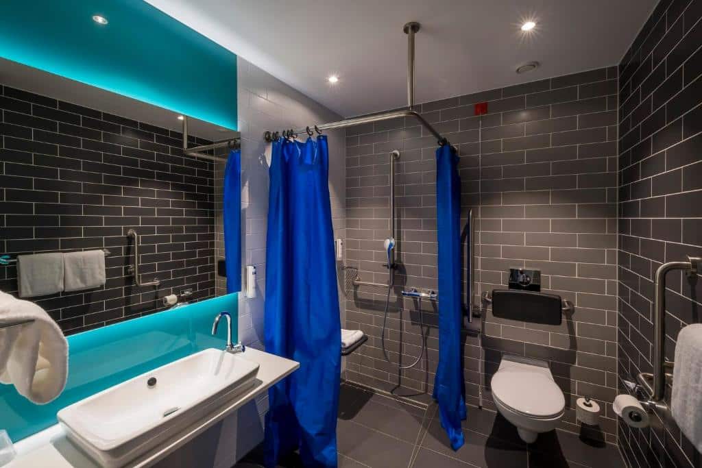 Casa de banho adaptada no Holiday Inn Express, com lavatório rebaixado, barras de apoio e corda de emergência.