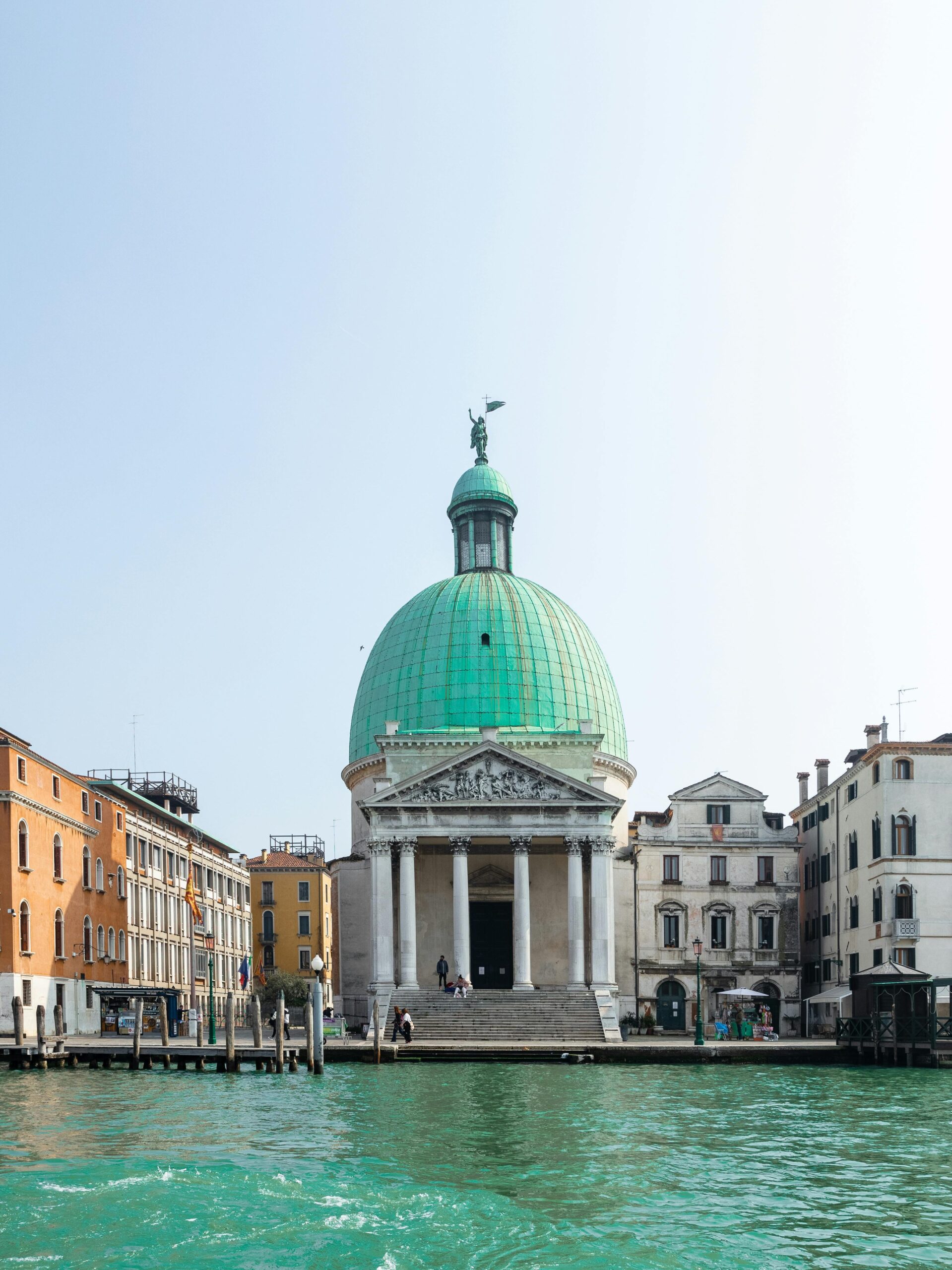 San Simeone Piccolo, com a sua imponente cúpula verde-esmeralda, numa praça com barcos no canal em Veneza, Itália