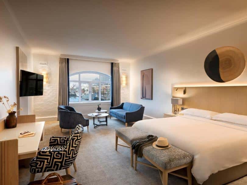 Quarto do Victoria & Alfred Hotel com cama grande, zona de estar, secretária, TV, janela e decoração em tons neutros.