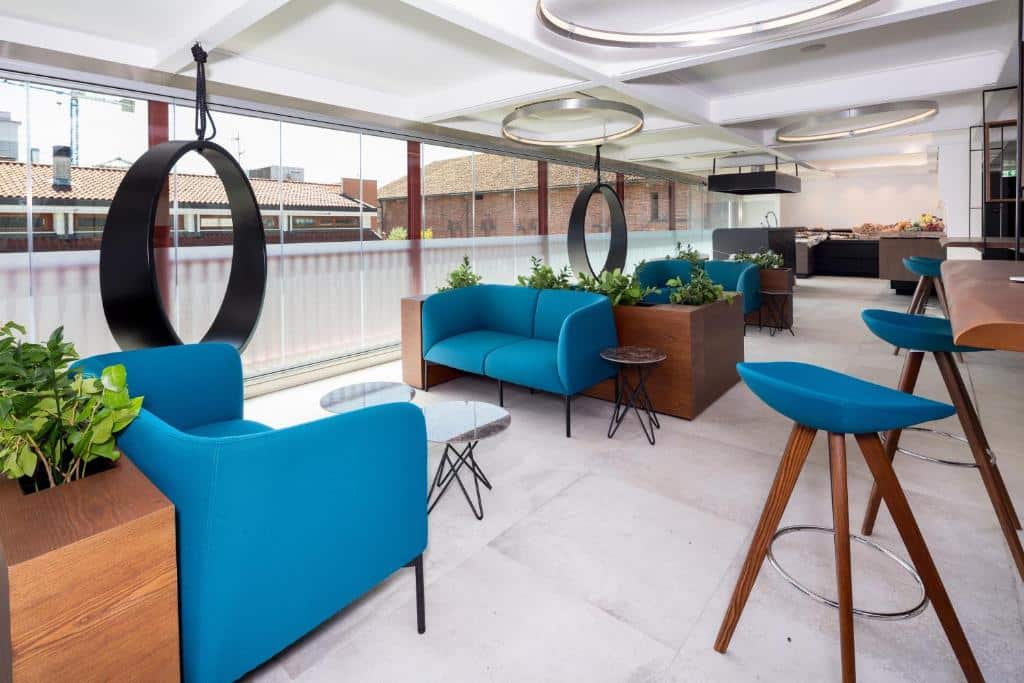 Sala de estar com sofás azuis, mobiliário em madeira e vista sobre a cidade no The Corner Duomo Hotel