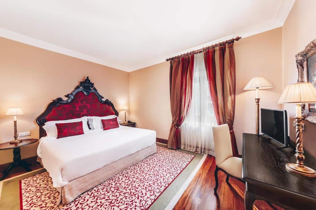 Quarto do Convento do Espinheiro com cama de casal, secretária e TV.