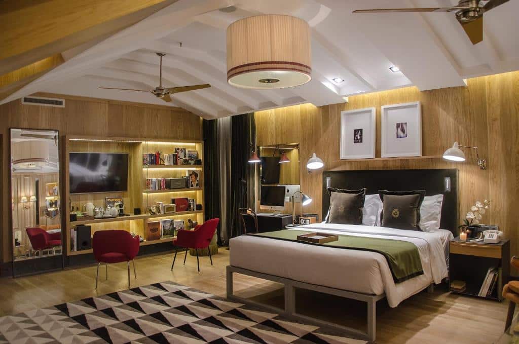 Quarto amplo com cama de casal queen size, espelho de corpo inteiro, ventoinhas de teto, candeeiro, painel com TV, duas poltronas e uma secretária, no Browns Central Hotel.