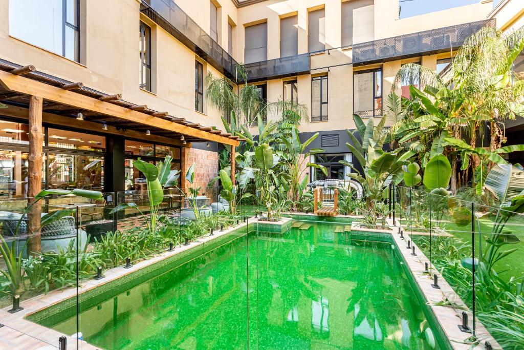 Zona exterior do Saman Hotel Boutique, com piscina cercada por vegetação tropical e edifícios de fachada em pedra com janelas.