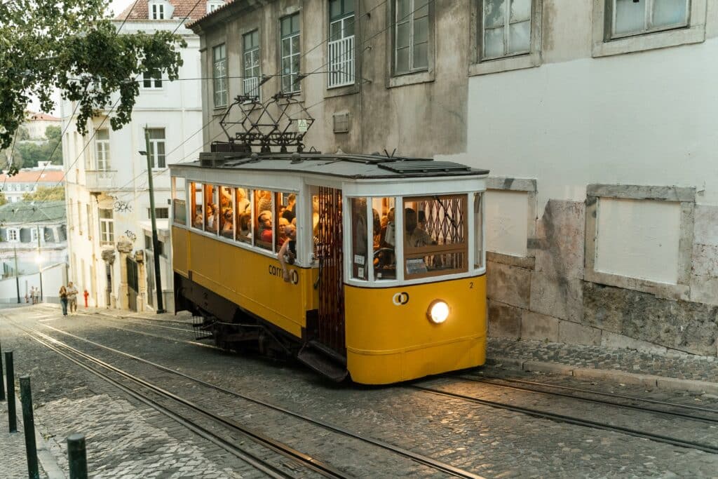 Elétrico amarelo, cheio de pessoas, a subir uma ladeira de Lisboa, um dos destinos mais visitados da Europa