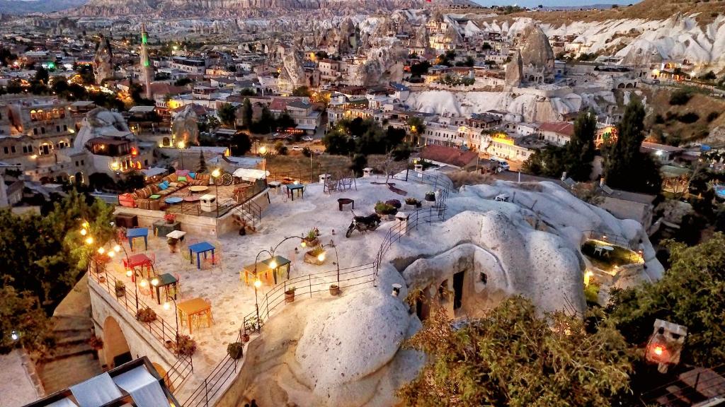 Vista aérea de uma localidade com habitações em caverna, zonas de estar ao ar livre e paisagem rochosa ao pôr do sol, no Traveller's Cave Hotel.