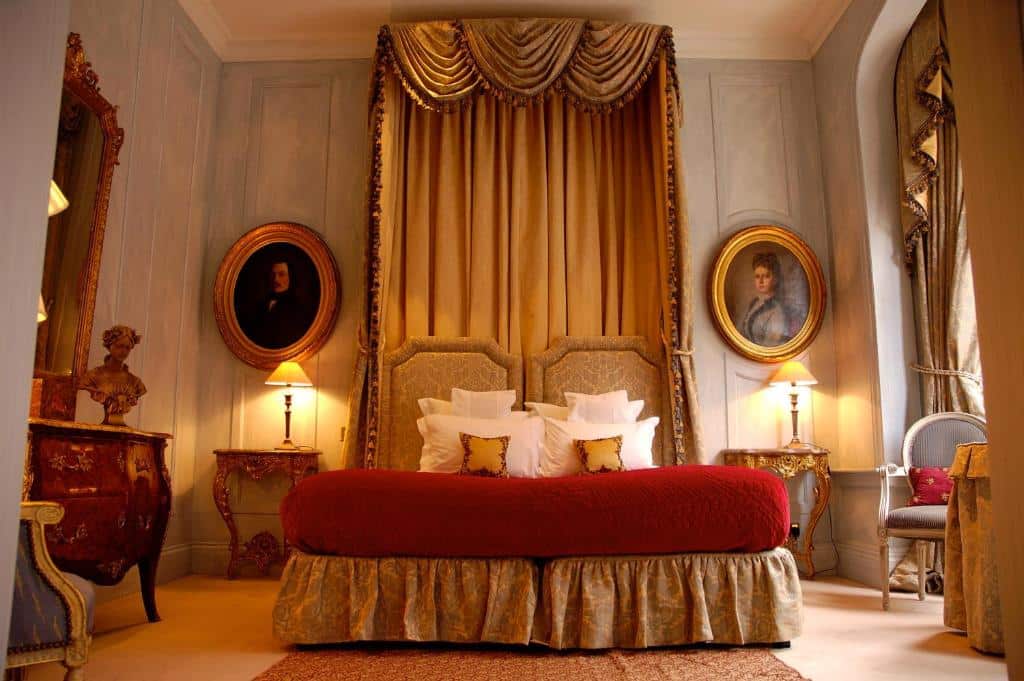 Quarto do San Domenico House com cama de casal e cabeceira com tecidos que sobem até ao teto, duas mesas de cabeceira com candeeiros, quadros nas paredes, poltronas e uma janela com cortinas.
