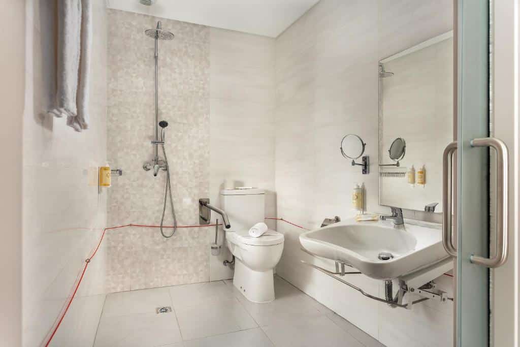 Casa de banho adaptada do Empire Marquês Hotel com barras de apoio, base de duche sem vidro, cordão de emergência e lavatório mais baixo sem móvel por baixo