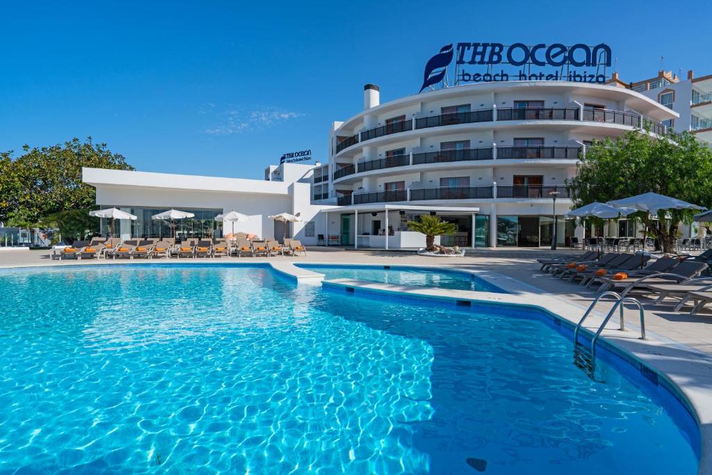 Piscina exterior do THB Ocean Beach com espreguiçadeiras em frente a um hotel moderno de vários andares.