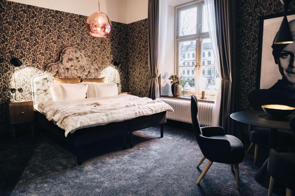 Quarto do NOFO Hotel com mesa redonda e cadeiras, cama de casal e cómodas.