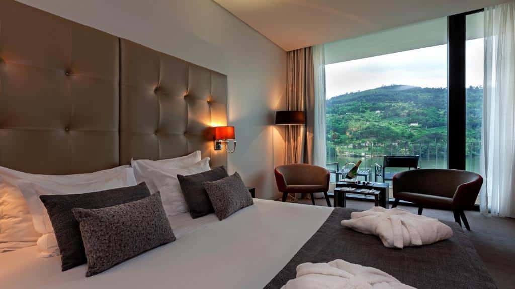 Quarto do Douro Royal Valley Hotel & Spa com cama de casal e duas poltronas.