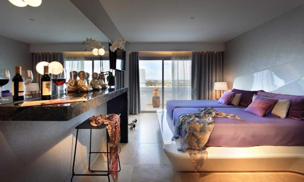 Quarto moderno do Ushuaia Ibiza Beach Hotel com uma cama grande, um balcão de bar e uma varanda com vista para o exterior.