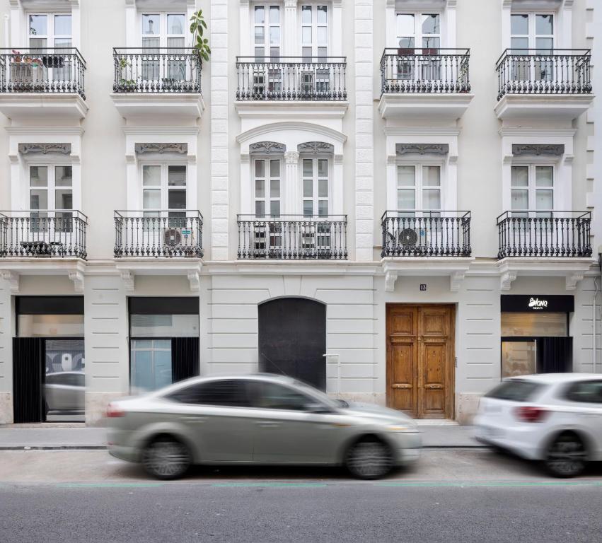 Fachada do edifício do Blanq Ruzafa, com varanda em estilo neoclássico e carros em movimento na rua em frente.