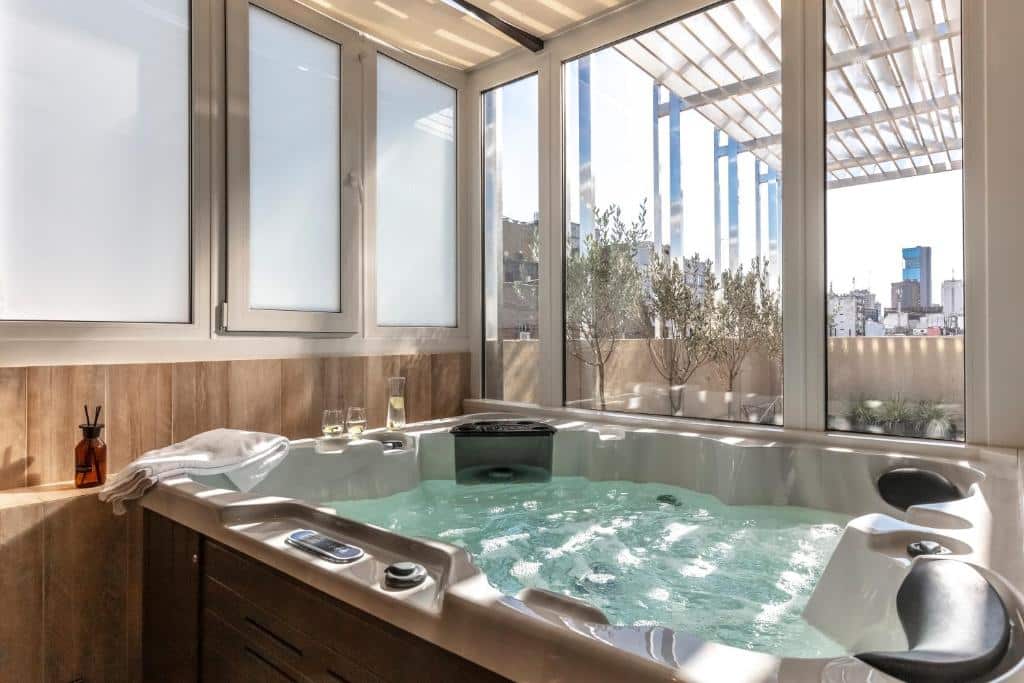 banheira de hidromassagem com vista do exterior, com raios de luz nas paredes de vidro, no Huinid Obelisco Hotel, um dos hotéis de luxo em Buenos Aires