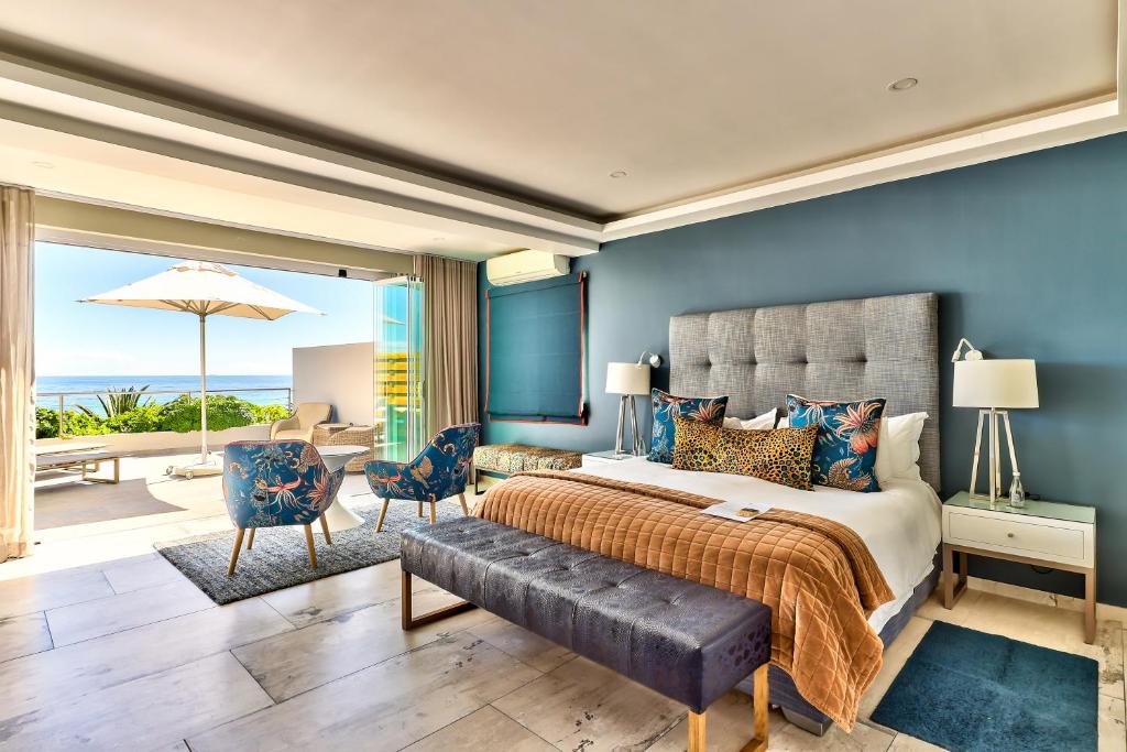 Quarto do Ocean View House com cama grande, zona de estar e portas abertas que dão para um pátio com vista para o mar.