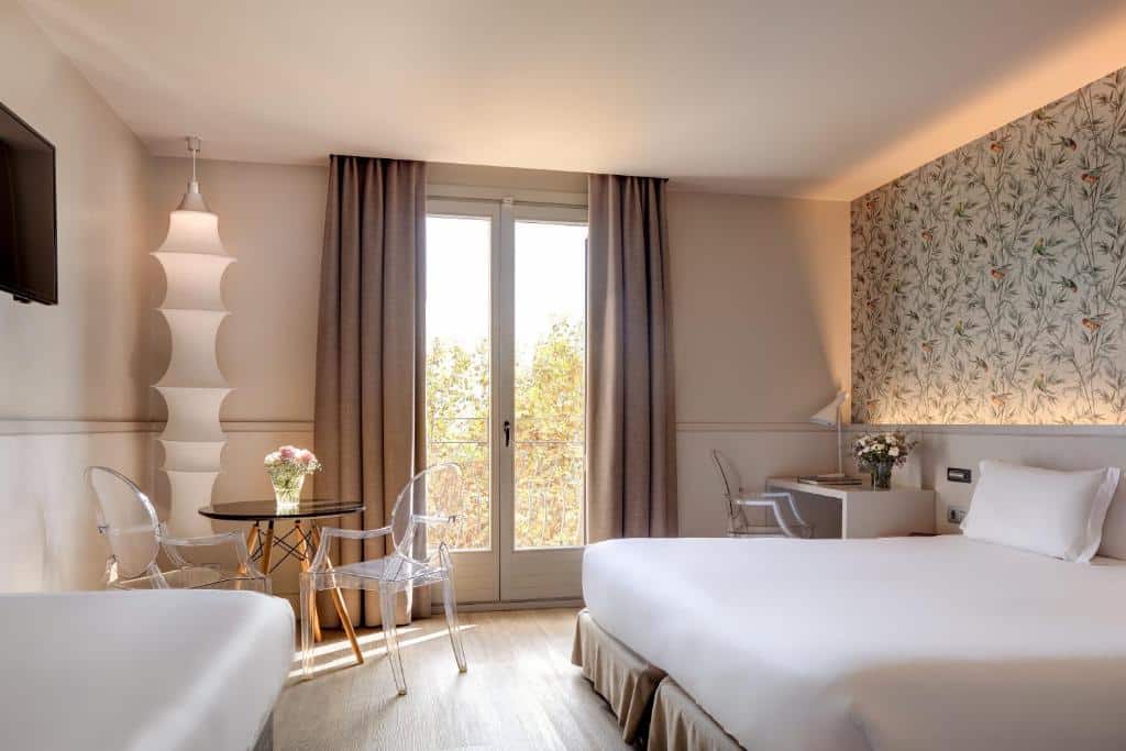Quarto do Duquesa de Cardona. A cama de casal encosta à parede, com mesas de cabeceira de ambos os lados, secretária com candeeiro e flores e uma mesa junto à grande janela com cortinas.