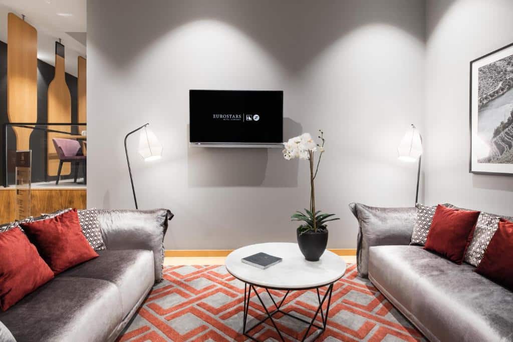 Sala do Eurostars Porto Centro com sofás cinzentos de cada lado, uma mesa redonda ao meio e uma TV na parede.