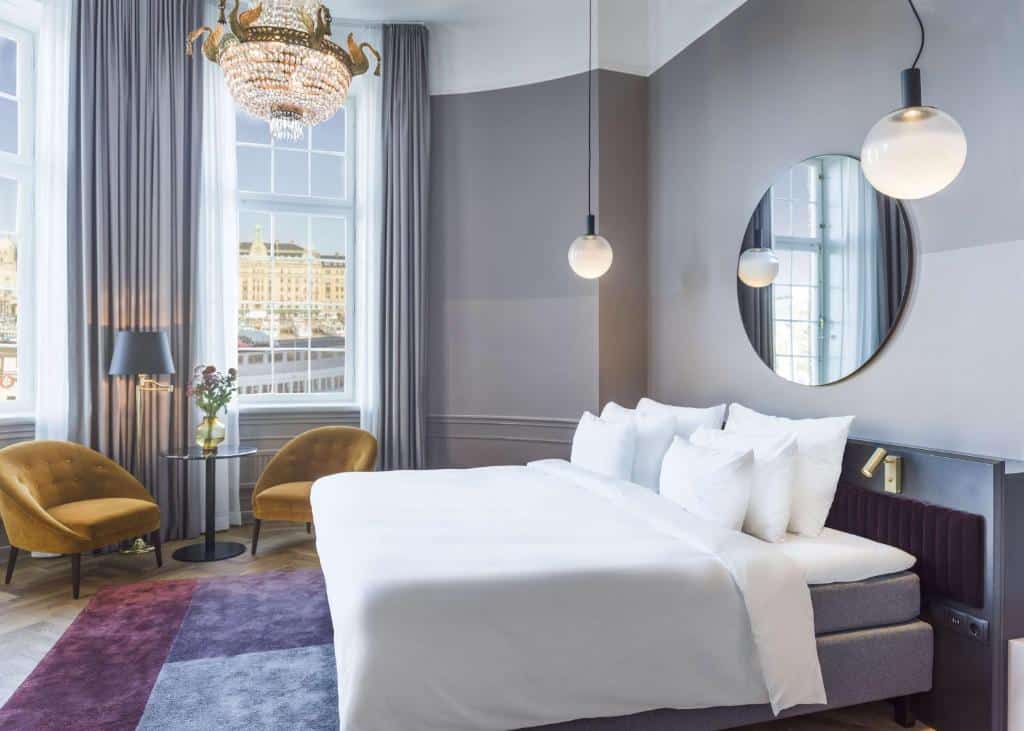 Quarto do Radisson Collection, Strand Hotel, com cama de casal e duas poltronas com mesa redonda.