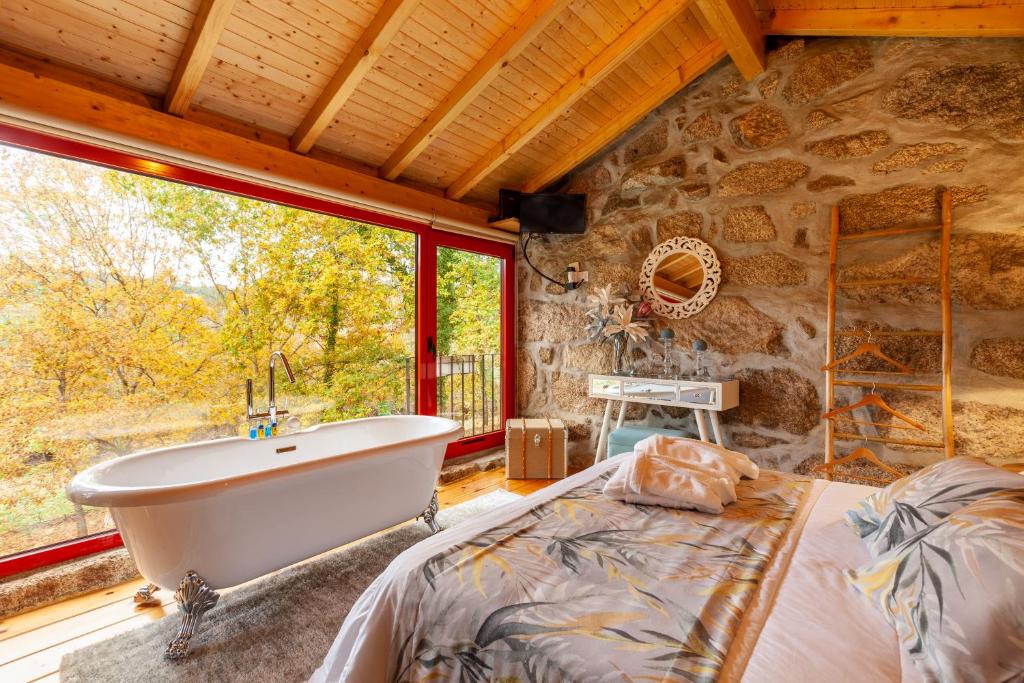 Quarto do Refúgio das Poldras, com cama de casal e banheira de hidromassagem em frente.