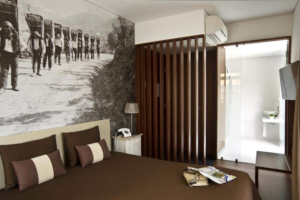 Quarto do Ribeira do Porto Hotel com cama de casal e, um pouco à frente, uma cómoda com TV na parede.