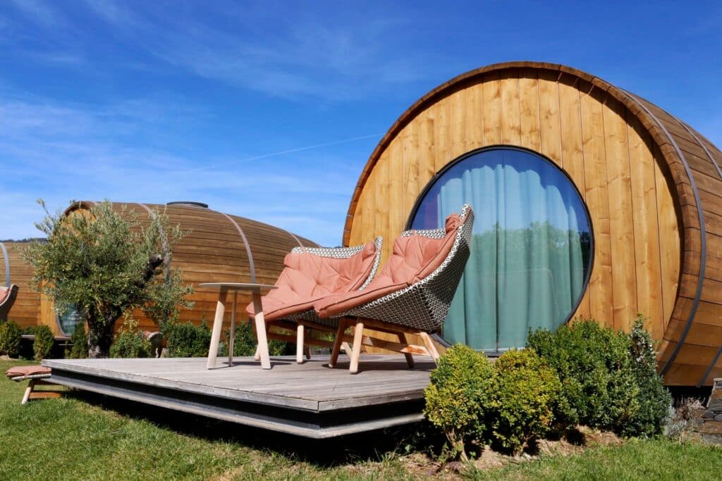 Alojamento em forma de barril de vinho do The Wine House Hotel – Quinta da Pacheca, com cadeira em frente.