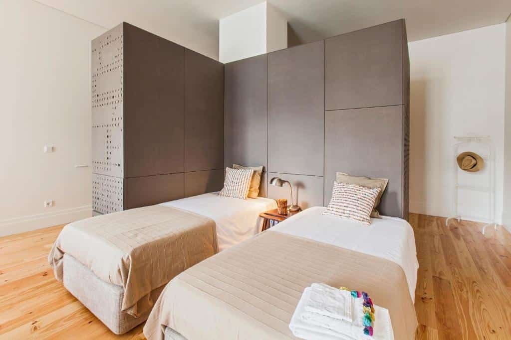 Quarto do bnapartments Loftpuzzle, com duas camas de solteiro à direita e uma cómoda de madeira ao centro com candeeiro.
