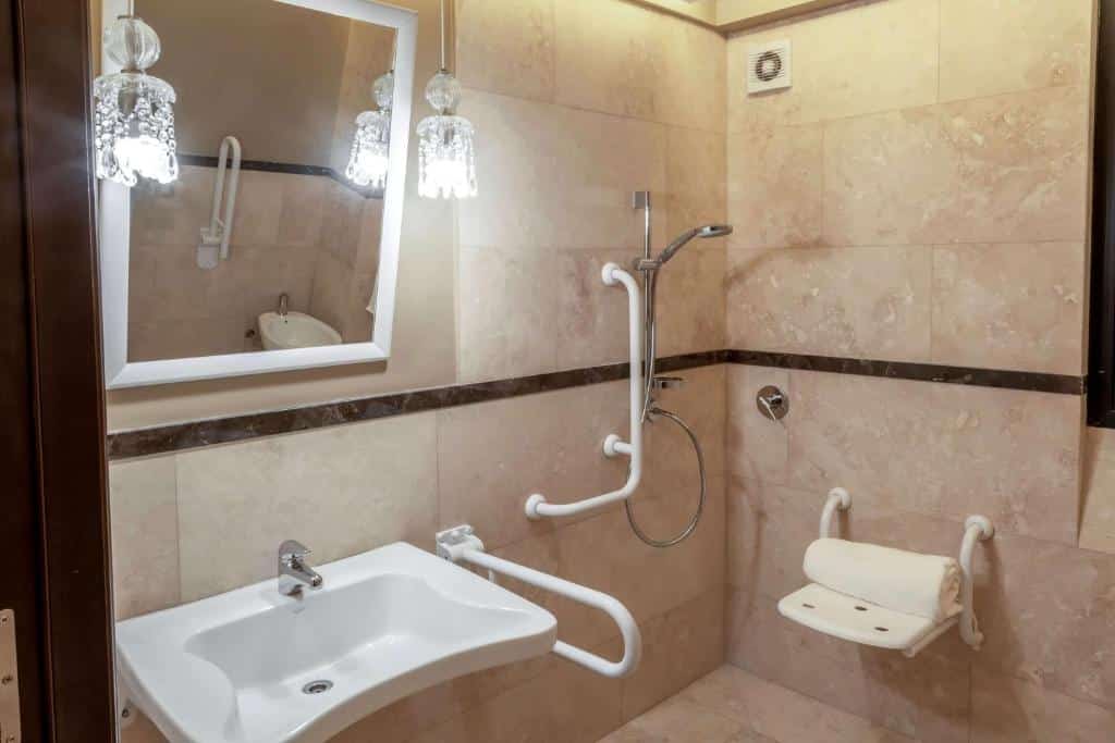 casa de banho adaptada no Esplendor by Wyndham Buenos Aires Tango, com barras de apoio, cadeira de banho, chuveiro de mão e lavatório mais baixo e aberto para facilitar o acesso