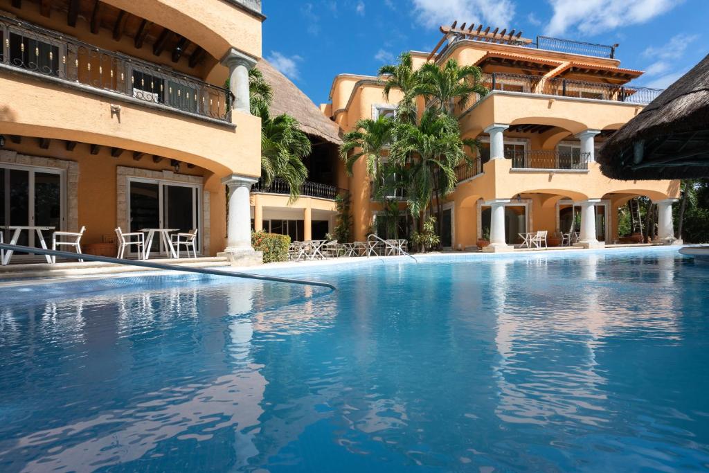 Piscina azul-turquesa no Eurostars Hacienda Vista Real, com arquitetura colonial e palmeiras tropicais.